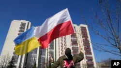 A man waves the Ukrainian and Polish flag during a demonstration in front of a building housing Russian diplomats in Warsaw, March 13, 2022. Poland says it has identified 45 Russian secret service officers and their associates who have enjoyed diplomatic status in Poland.