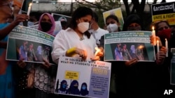 Indians hold placards and candles during a protest against banning Muslim girls wearing hijab from attending classes at some schools in the southern Indian state of Karnataka, in Bengaluru, Karnataka state, India, Feb. 19, 2022.