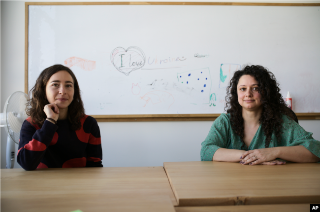 Volunteers Burcak Sevilgen, right, and Faina Karlitski pose for a photo at a space where they organized two school classes for Ukrainian refugees in Berlin, Germany, Monday, March 21, 2022. (AP Photo/Markus Schreiber)