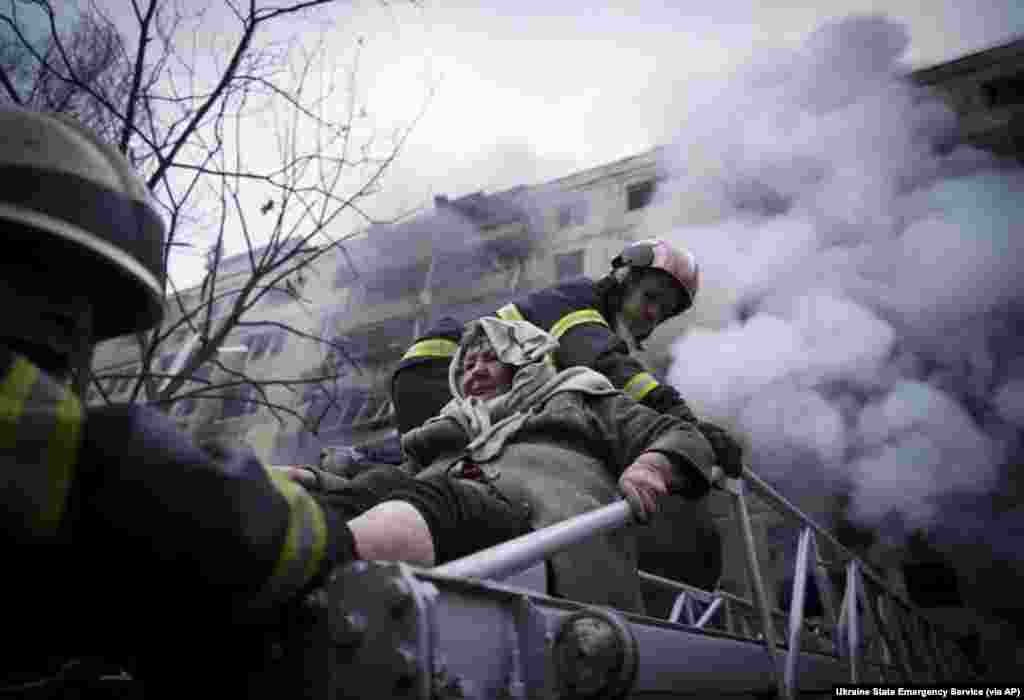 Firefighters evacuate an elderly woman from an apartment building hit by shelling in Kyiv, Ukraine, March 14, 2022.