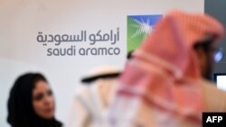 FILE - In this Jan. 25, 2016, photo, Saudi and Foreign investors stand in front of the logo of Saudi state oil giant Aramco during the 10th Global Competitiveness Forum in the capital, Riyadh.