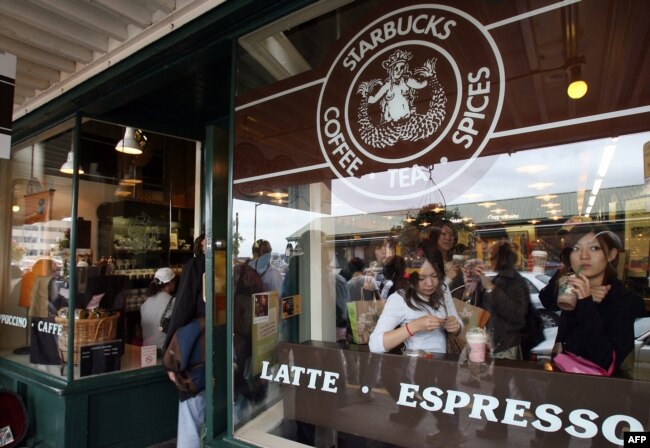 Turis Jepang menikmati kopi di kedai kopi pertama Starbucks di Pike Place Market Seattle, 30 September 2006. Gerai ini berdiri sejak 1971. (AFP PHOTO/GABRIEL BOUYS)