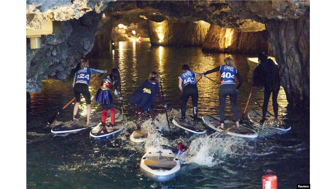 Para peserta BAT Race, perlombaan Stand Up Paddle (SUP) dari Tur Danau Alpine, bertanding di danau bawah tanah terbesar di Eropa, St-Leonard dekat Sion, Swiss, 12 Maret 2022. (REUTERS/Denis Balibouse)