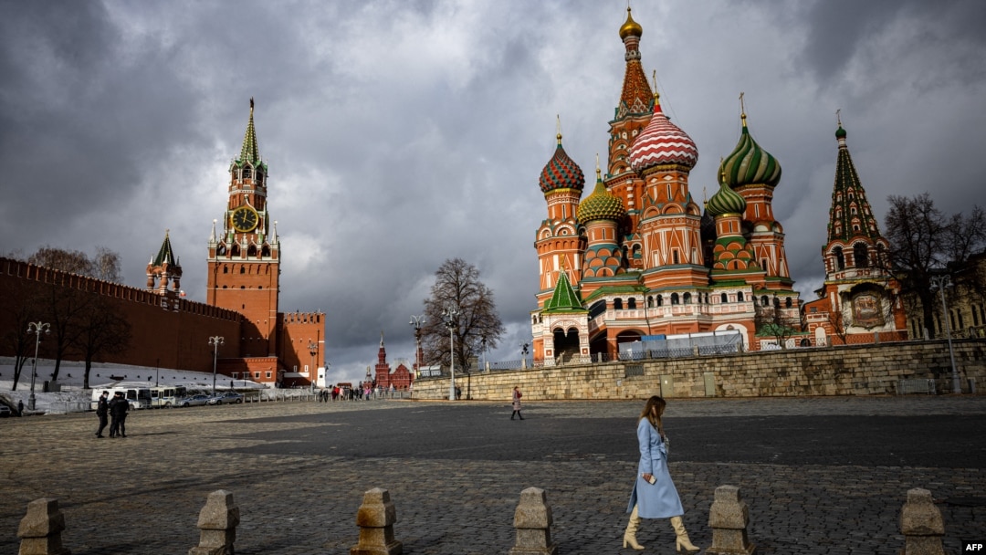 FILE - A woman walks under cloudy skies near the Kremlin and St. Basil's Cathedral in central Moscow, Russia, Feb. 22, 2022.