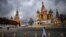 FILE - A woman walks under cloudy skies near the Kremlin and St. Basil's Cathedral in central Moscow, Russia, Feb. 22, 2022. 