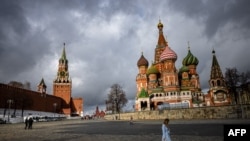 FILE - A woman walks near the Kremlin and St. Basil's Cathedral in central Moscow, Russia, Feb. 22, 2022. 