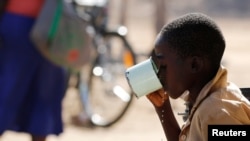 FILE - A child drinks water from a cup in drought-hit Masvingo, Zimbabwe.