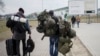 FILE - A man carries combat gear as he leaves Poland to fight in Ukraine, at the border crossing in Medyka, Poland, March 2, 2022.