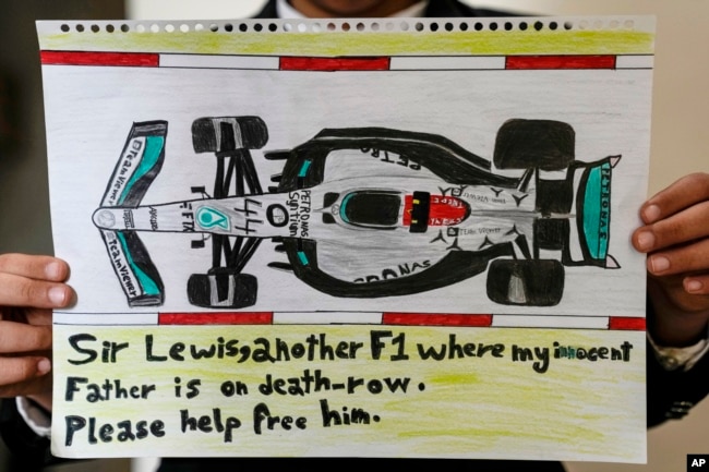 Ahmed (12 tahun), putra Mohammed Ramadhan, di Manama, Bahrain, Kamis, 17 Maret 2022, memegang gambar mobil F1 bertuliskan pesan untuk pembalap F1 Lewis Hamilton, agar membantu membebaskan ayahnya yang berada di penjara dan terancam hukuman mati. (AP)
