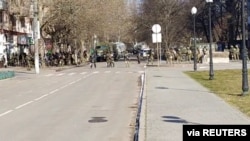 Live-streamed footage shows what appears to be Russian troops standing in the distance with a Z-marked military vehicle as people protest against Russia's invasion of Ukraine, in Kherson, Ukraine, March 13, 2022, in this still image from a social media.