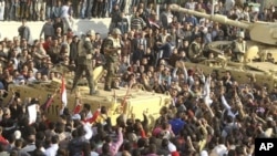 Armed soldiers look down on protesters surrounding military vehicles in Tahrir Square in Cairo, Egypt, February 2, 2011
