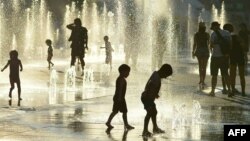 Des enfants jouent avec les fontaines d'eau de la Place des Arts à Montréal, le 3 juillet 2018