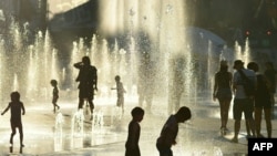 Children play in the water fountains at the Place des Arts in Montreal, Canada on a hot summer day