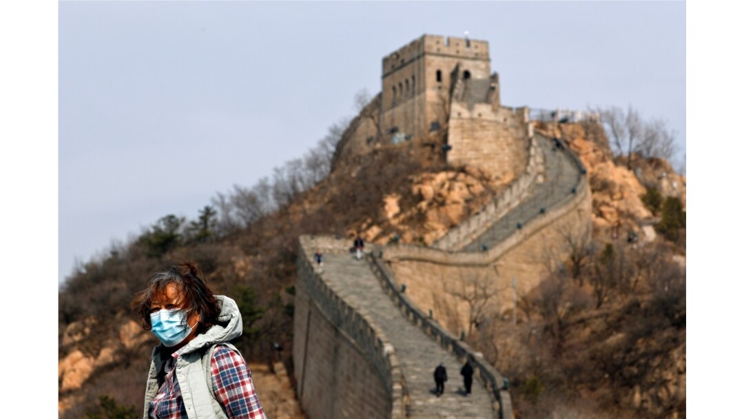 A woman wearing a protective face mask visits the Badaling Great Wall of China after it reopened for business, March 24, 2020.