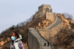 A woman wearing a protective face mask visits the Badaling Great Wall of China after it reopened for business, March 24, 2020.