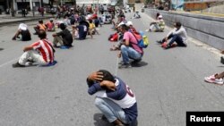 Personas que supupuestamente violaron las medidas de distancia social son castigadas bajo el sol en una calle de Caracas por las fuerzas de seguridad de Venezuela el 5 de agosto de 2020.