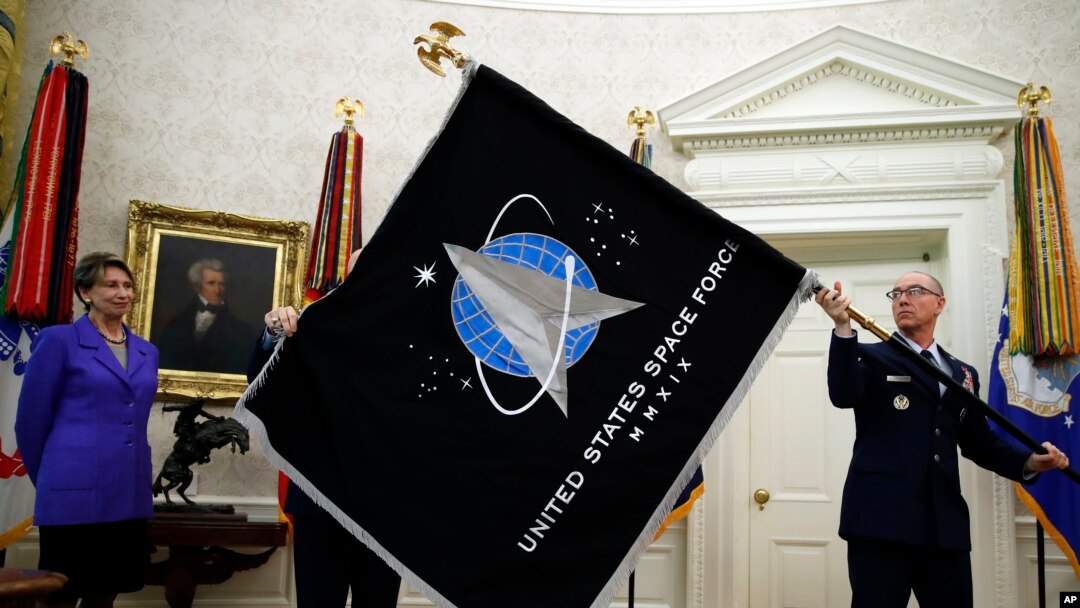 Secretary of the Air Force Barbara Barrett, left, watches Chief Master Sgt. Roger Towberman hold the United States Space Force flag as it is presented in the Oval Office of the White House, May 15, 2020, in Washington.