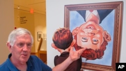 FILE - Cartoonist Brian Walker talks about the artistic history of MAD magazine ahead of the opening of an exhibit on MAD artists and illustrators, May 3, 2018, in Columbus, Ohio. MAD has announced that it will be leaving newsstands in fall 2019.