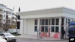 A security staff stands near the entrance of the US embassy in Greece some hours after an anarchist group threw red paint, in Athens, Jan. 7, 2019. 