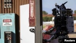 FILE - An earlier version of Boston Dynamics' Atlas robot opens a door during the Defense Advanced Research Projects Agency (DARPA) Robotic Challenge in Pomona, California, June 6, 2015. 