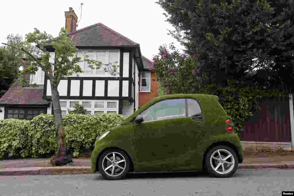 A car covered in artificial grass is seen parked in a residential street in London.