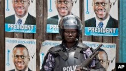 A Ugandan riot policeman blocks the gate of the party headquarters of opposition leader Kizza Besigye, shortly after raiding the premises for the second time in a week, Kampala, Uganda, Feb. 22, 2016. 