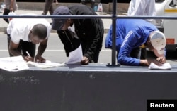 FILE - Zimbabweans fill out application forms outside immigration offices in Johannesburg, South Africa, Dec. 31, 2010.