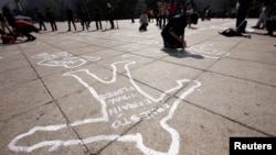 FILE - Demonstrators lie on silhouettes that represent a victim of violence in Mexico City, Mexico, Dec. 11, 2016.