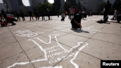 Demonstrators lie on silhouettes that represent a victim of violence that was painted by activists of the organization Nos hacen falta (We are missing them), during a demonstration demanding justice for the victims of violence and drugs in Mexico City, Dec. 11, 2016. 