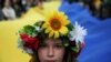 A young girl looks at a camera as people carry a huge Ukrainian flag during a peaceful demonstration, "Solidarity with Ukraine," in Krakow, on April 24, 2022. (Jakub Wlodek/Agencja Wyborcza.pl/Reuters)