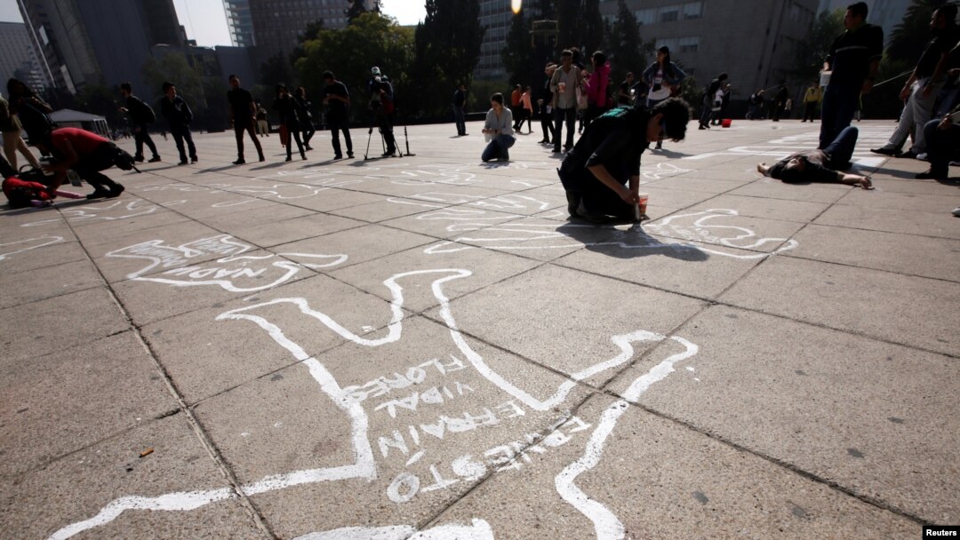 Demonstrators lie on silhouettes that represent a victim of violence that was painted by activists of the organization Nos hacen falta (We are missing them), during a demonstration demanding justice for the victims of violence and drugs in Mexico City, Dec. 11, 2016. 