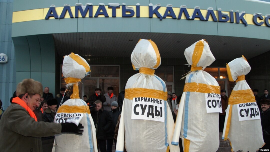 FILE - A supporter of Kazakhstan's opposition Democratic Choice of Kazakhstan sets up dummies of judges in front of a court building in Almaty, Feb. 9, 2005. 