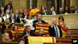 Anggota parlemen dari oposisi Catalan, memegang bendera nasional Spanyol dan Estelada sebelum nmeninggalkan majelis tersebut untuk memboikot pemungutan suara di parlemen Catalan, Barcelona, Spanyol, Jumat, 27 Oktober 2017.