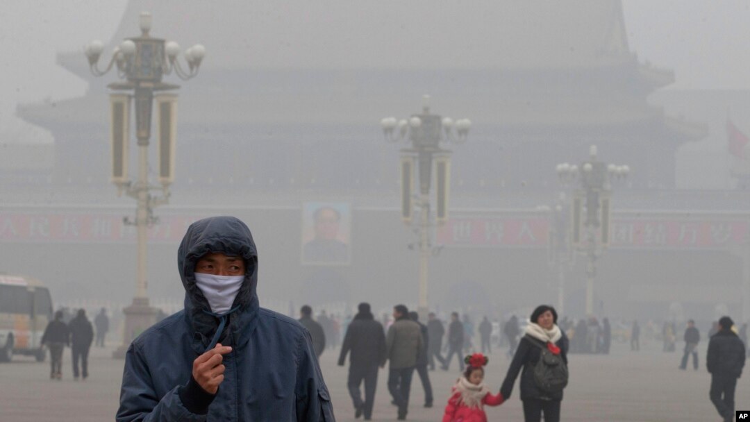 Seorang pria menggunakan masker di tengah asap tebal di Alun-Alun Tiananmen, Beijing (29/1). (AP/Ng Han Guan)