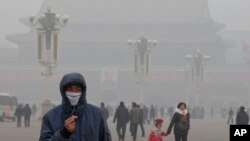 Seorang pria menggunakan masker di tengah asap tebal di Alun-Alun Tiananmen, Beijing (29/1). (AP/Ng Han Guan)