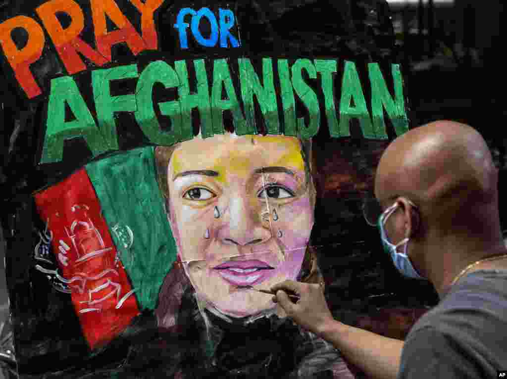 Students of an art school make paintings with messages in solidarity with the people of Afghanistan on a pavement in Mumbai, India.