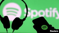 FILE: A smartphone and a headset are seen in front of a screen projection of Spotify logo, in this picture illustration taken April 1, 2018. 