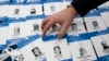 FILE - An activist arranges symbolic press passes with the names, pictures and media affiliations of Turkish journalists accused by the Turkish government of having aided a failed 2016 coup, during a protest in Sofia, Bulgaria, March 22, 2018.