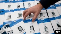 FILE - An activist arranges symbolic press passes with the names, pictures and media affiliations of Turkish journalists accused by the Turkish government of having aided a failed 2016 coup, during a protest in Sofia, Bulgaria, March 22, 2018.