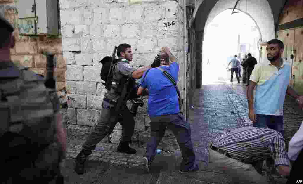 AFP photographer Menahem Kahana (C) is roughed up by an Israeli policeman during a demonstration in a street in the Muslim quarter of Jerusalem&#39;s Old City.&nbsp;Israel took a rare and drastic step of barring Palestinians from the Old City as tensions mounted following attacks that killed two Israelis and wounded a child.