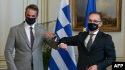 PM Yunani Kyriakos Mitsotakis (kiri) dan Menlu Jerman Heiko Maas (kanan) saling memberi salam dengan siku mereka menjelang pertemuan di Maximos Mansion, Athena, Yunani, 25 Agustus 2020. 