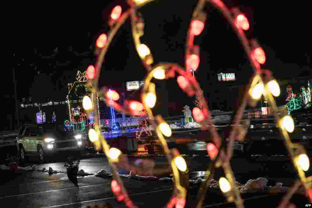 Al fondo los autos atraviesan el &quot;Winter in Wilmington Light Show&quot; en Wilmington, Delaware, el 18 de diciembre de 2020. [AFP]