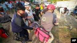 Rescue personnel move an injured migrant woman from the site of an accident near Tuxtla Gutierrez, Chiapas state, Mexico, Dec. 9, 2021. 