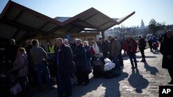 People wait in a line to board a train leaving for Lviv in Ukraine at the train station in Przemysl, Poland, March 14, 2022.