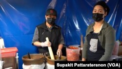 Nantutchakorn (L) and Keerati (R) Jaruthammaorn, the owner of The Best SomTum Thai vendor, prepare a green papaya salad (Som Tum) for a customer at Wat Thai (Thai Temple) of Los Angeles food court, Los Angeles, CA.