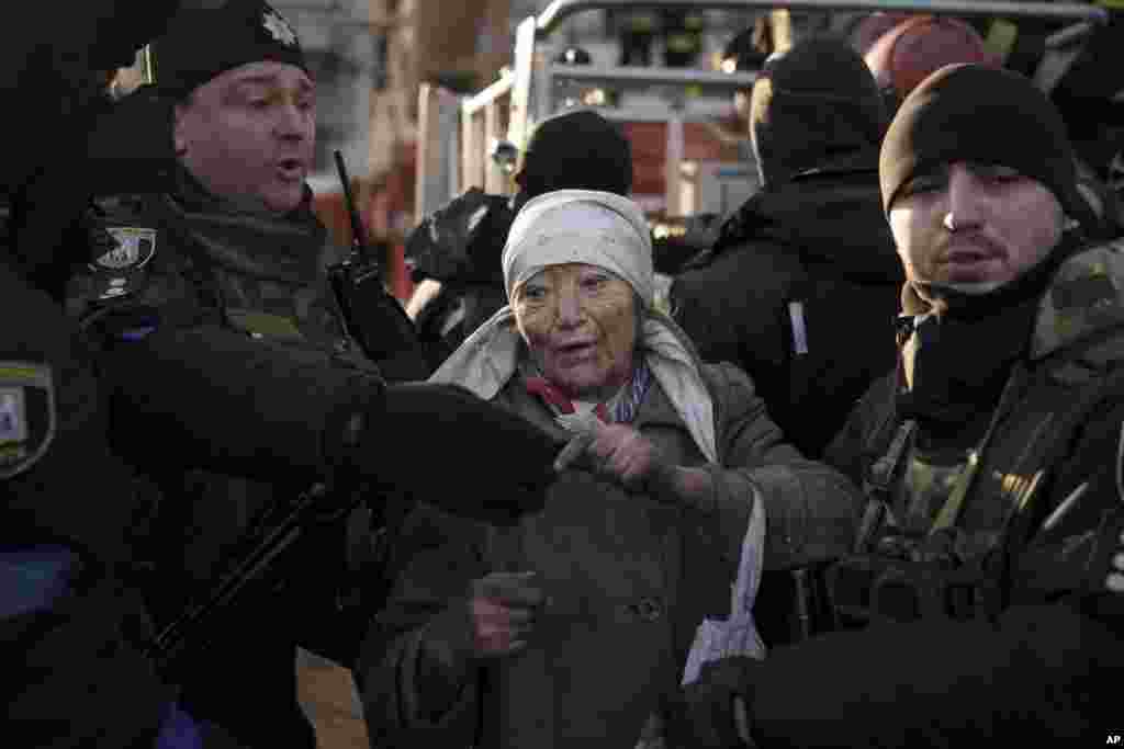 Policemen helps an elderly woman after she was rescued by firefighters from her apartment after bombing in Kyiv, March 15, 2022.