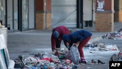 FILE - Two local women sort through debris following a looting at Diepkloof Square, Soweto, Johannesburg, July 14, 2021.