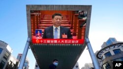 Chinese President Xi Jinping is seen on a live broadcast of the opening ceremony for the National People's Congress at a mall on March 5, 2022, in Beijing. 