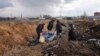 Ljudi vuku mrtvo telo ubijenog čoveka ka zajedničkoj grobnici, pošto su pojedinačne sahrane nemoguće usled teškog bombardovanja koje ruske snage izvode na grad Mariupolj, u Mariupolju, 9. marta 2022.