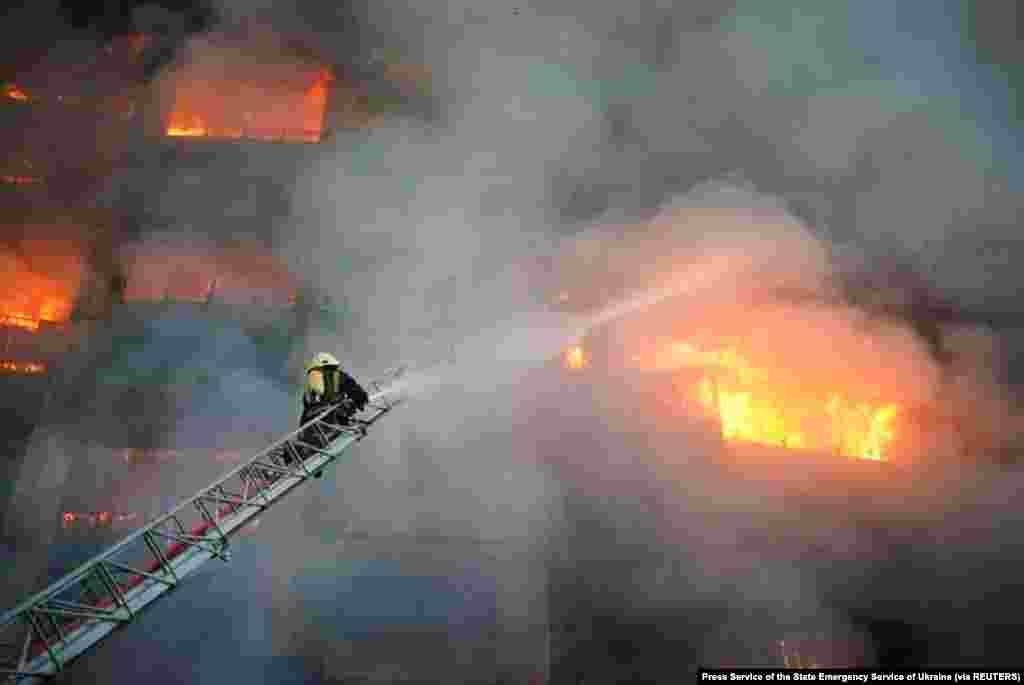 A rescuer puts out a fire in a residential building damaged by Russian shelling, in Kyiv, March 15, 2022.
